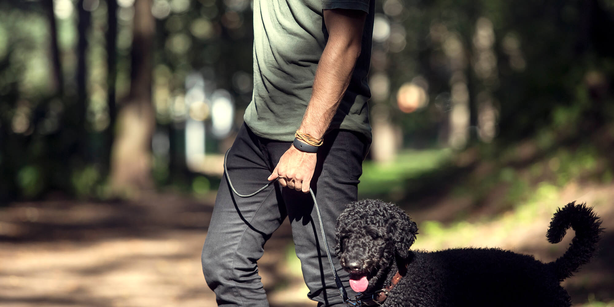 Chłopak idzie na spacer z psem i ma na sobie czarną bransoletkę AMBRIO o prostym kroju